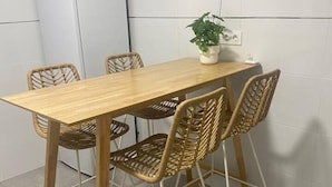 A dining table with four wicker chairs, a potted plant, and a power outlet on the wall. - 102B Poniente Mágico by R2R Consulting (Gijón)