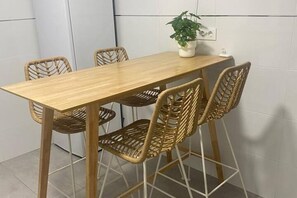 A dining table with four wicker chairs, a potted plant, and a power outlet on the wall. - 102B Poniente Mágico by R2R Consulting (Gijón)