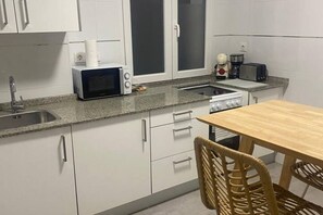 A kitchen with white cabinets, a microwave, a toaster, and a stove. - 102B Poniente Mágico by R2R Consulting (Gijón)
