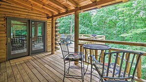 A wooden deck with a glass door leading to a patio area, surrounded by a forest.
