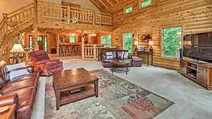 A spacious log cabin interior with a living room, dining area, and a balcony.