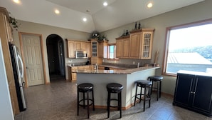 A kitchen with a central island, wooden cabinets, a microwave, and a large window. - Lakefront property w dock & amazing sunsets  (Sunrise Beach)
