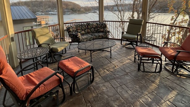 A covered outdoor seating area with stone flooring, a ceiling fan, and a view of a lake and hills. - Lakefront property w dock & amazing sunsets  (Sunrise Beach)
