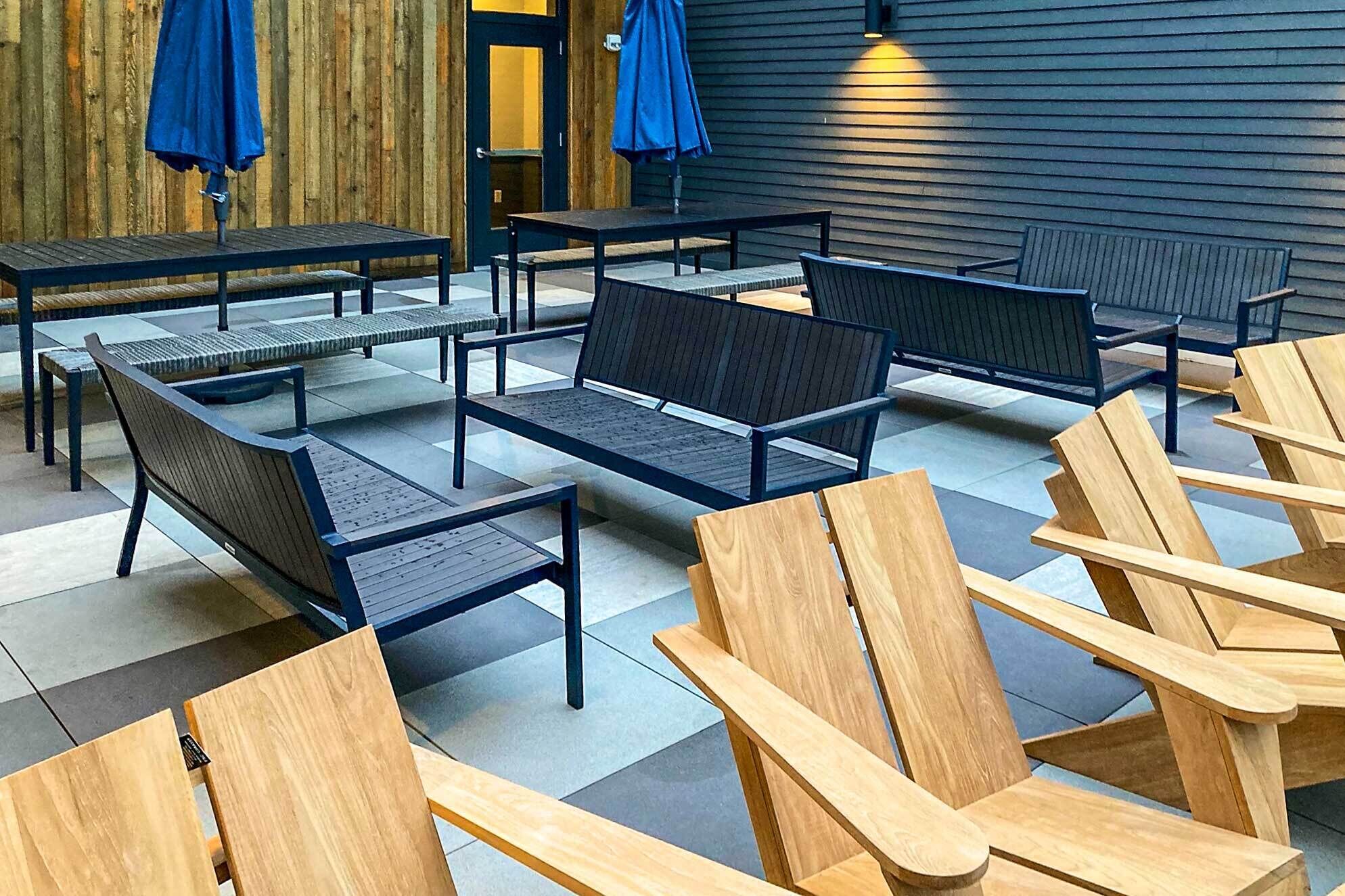 A seating area with wooden chairs and benches, a wooden wall, and a door with a glass panel.