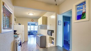 A kitchen with white cabinets, a microwave, and a stove. There is a window with blinds and a door leading to another room. - Steps to Beach & Bites: Catalina Island Retreat! (Avalon)
