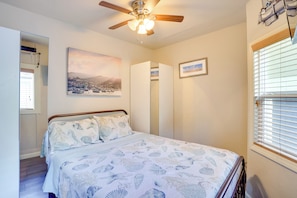 A bedroom with a bed, a ceiling fan, a window with blinds, and a painting on the wall. - Steps to Beach & Bites: Catalina Island Retreat! (Avalon)