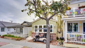 A residential street with houses, a tree, and a golf cart parked on the sidewalk. - Steps to Beach & Bites: Catalina Island Retreat! (Avalon)