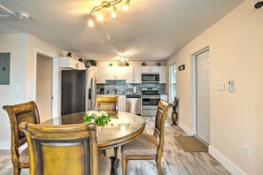 A modern kitchen with white cabinets, stainless steel appliances, and a dining area with a glass table and wooden chairs.