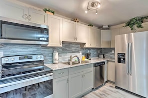 A modern kitchen with stainless steel appliances, white cabinetry, and a tiled backsplash. - Inviting Apartment < 2 Mi to Riviera Beach! (West Palm Beach)
