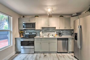 A modern kitchen with white cabinets, stainless steel appliances, a tiled backsplash, and a window providing natural light. - Inviting Apartment < 2 Mi to Riviera Beach! (West Palm Beach)