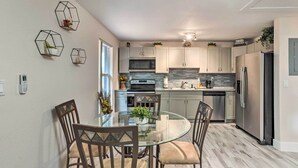 A modern kitchen with white cabinets, stainless steel appliances, and a glass dining table. - Inviting Apartment < 2 Mi to Riviera Beach! (West Palm Beach)