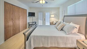Ein Schlafzimmer mit Bett, Deckenventilator, Fernseher an der Wand und Kleiderschrank.