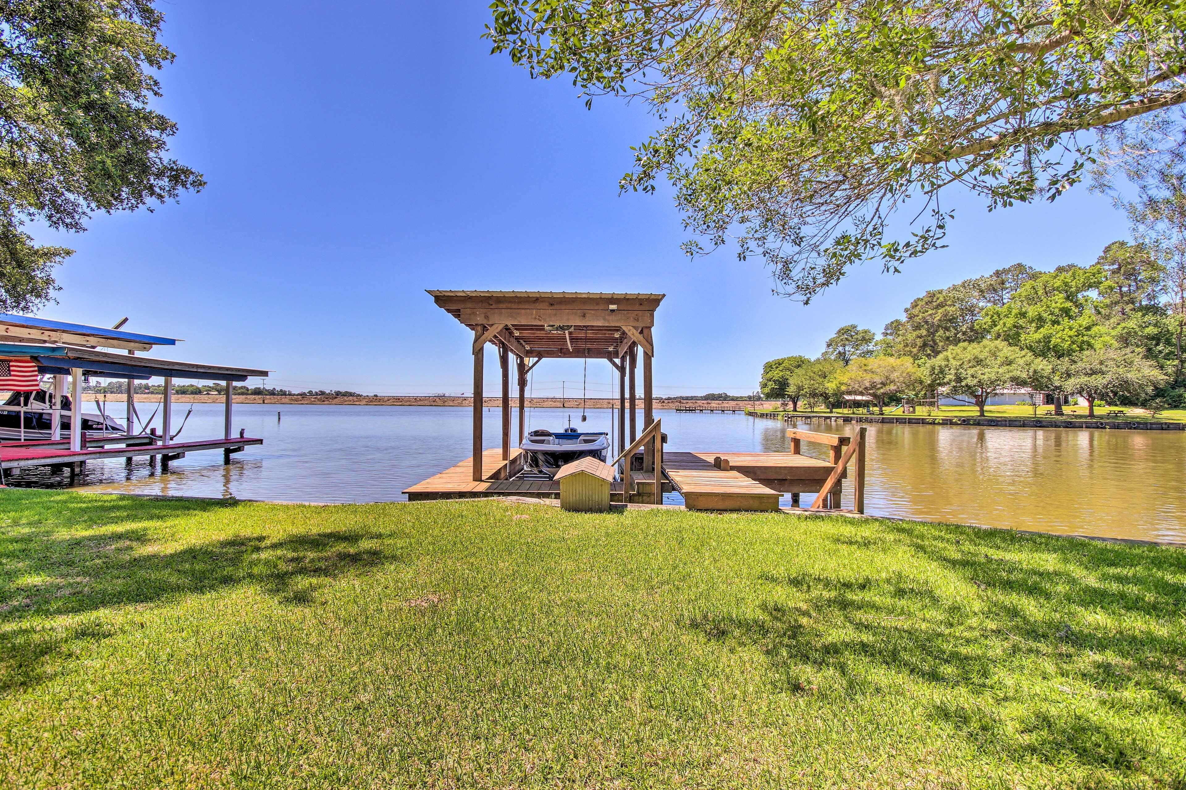 A lakeside gazebo with a dock, a boat, and a small shed.
