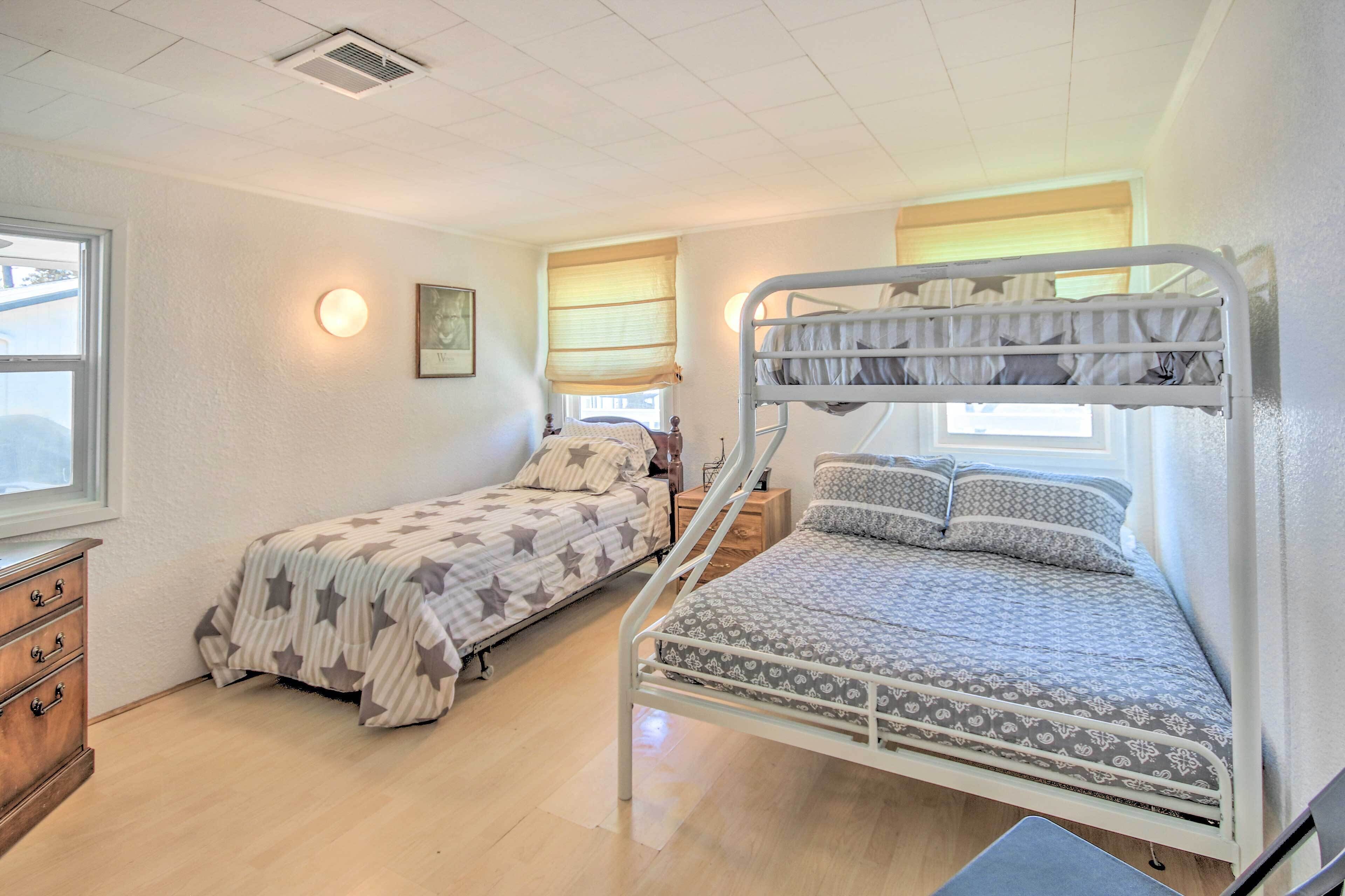 Una habitación con dos literas, un aparador de madera y una ventana con persianas.