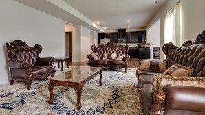 A spacious living room with a large, ornate coffee table, leather sofas, and a patterned rug. - Spacious Home w/ Fireplace - Near Golf! (Brownsburg)
