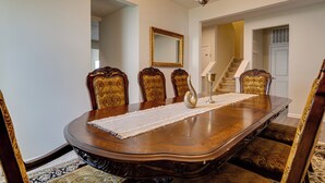 A formal dining room with a large wooden table, ornate chairs, a chandelier, and a mirror on the wall. - Spacious Home w/ Fireplace - Near Golf! (Brownsburg)
