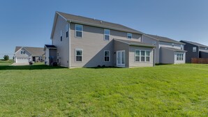 A two-story residential building with a sloped roof, multiple windows, and a front yard. - Spacious Home w/ Fireplace - Near Golf! (Brownsburg)