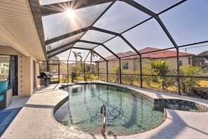 A swimming pool with a glass enclosure, a barbecue area, and a view of neighboring houses. - Punta Gorda Canal Home w/ Private Pool! (Punta Gorda)