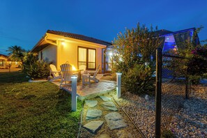 A house with a patio, outdoor seating, and a well-lit entrance. - Punta Gorda Canal Home w/ Private Pool! (Punta Gorda)