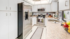 A modern kitchen with stainless steel appliances, white cabinetry, and granite countertops. - Punta Gorda Canal Home w/ Private Pool! (Punta Gorda)