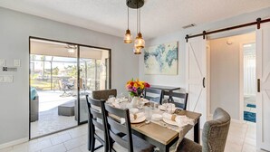 A dining area with a table set for four, a sliding glass door leading to an outdoor patio, and a ceiling fan. - Punta Gorda Canal Home w/ Private Pool! (Punta Gorda)