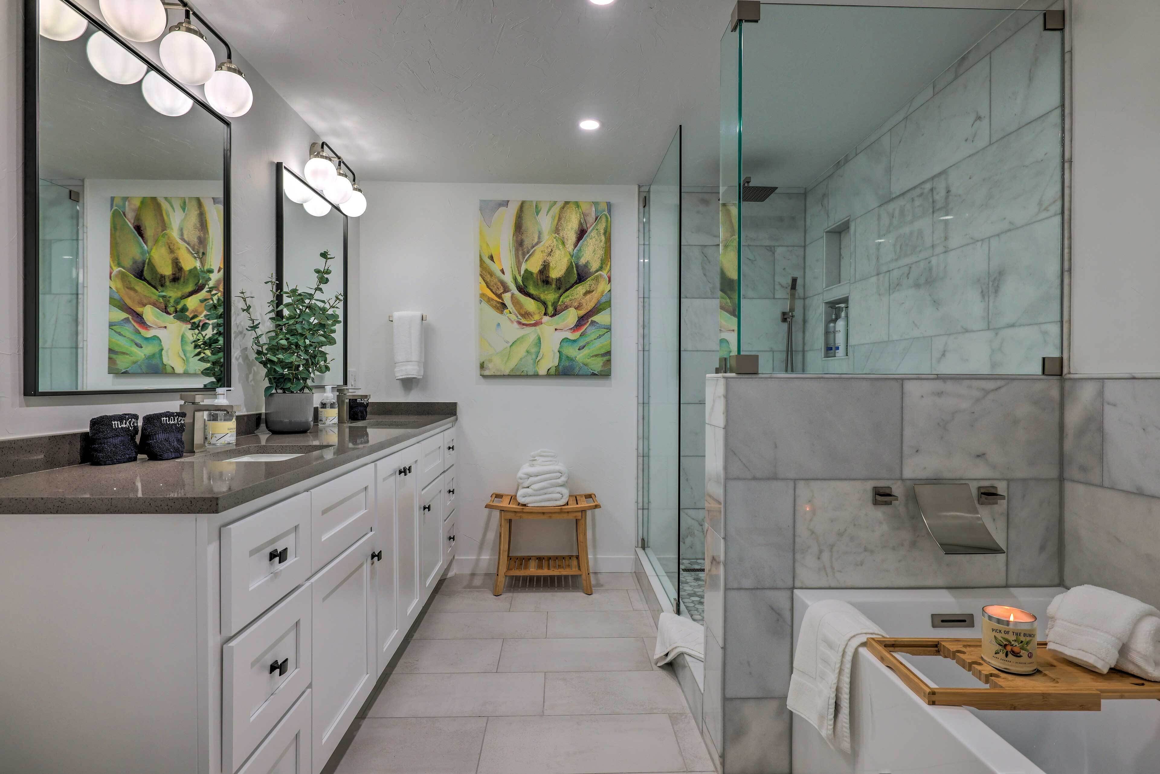 A modern bathroom with a vanity, a shower area, and a large mirror with lights.