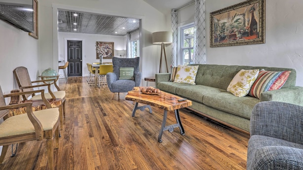 Una sala de estar con una mesa de centro de madera, sofá verde y sillas de madera.