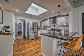 A modern kitchen with white cabinets, a central island with bar stools, a skylight, and stainless steel appliances. - Fredericksburg Getaway w/ Covered Deck & Fire Pit! (Fredericksburg)