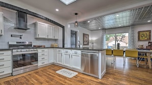 Una cocina moderna con armarios blancos, electrodomésticos de acero inoxidable y piso de madera.