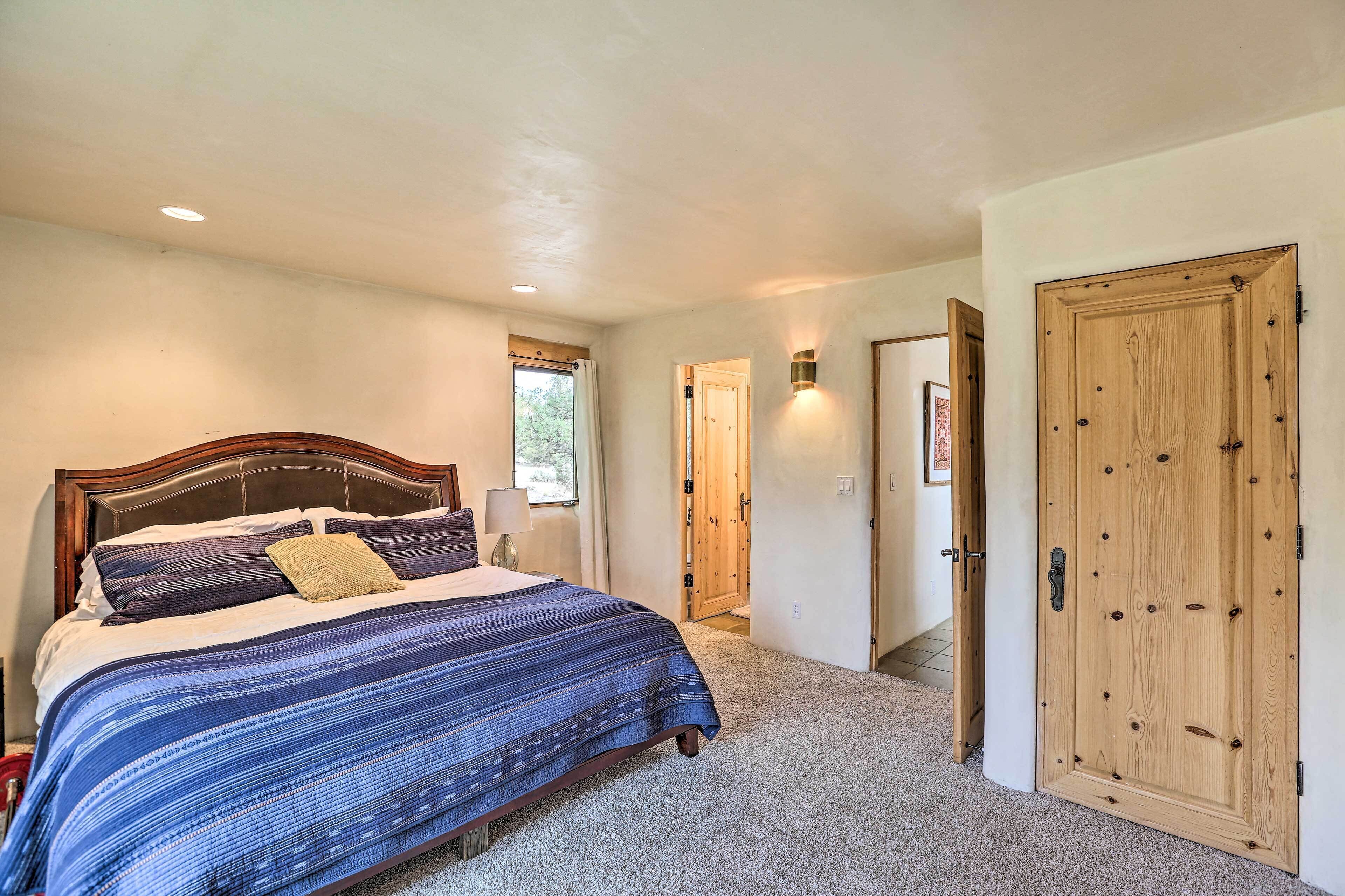 A bedroom with a large bed, a wooden door, and a hallway leading to another room.