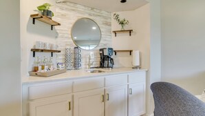 Une cuisine moderne avec des meubles blancs, une machine à café et un miroir au-dessus du plan de travail.