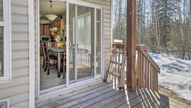 A wooden deck with a sliding glass door leading to a kitchen area with a dining table and chairs. - Peaceful Alaskan Escape: 13 Mi to Fairbanks! (Fairbanks)