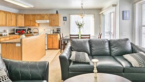 A modern kitchen with wooden cabinets, a central island, and a dining area with a black leather sofa and a table. - Peaceful Alaskan Escape: 13 Mi to Fairbanks! (Fairbanks)