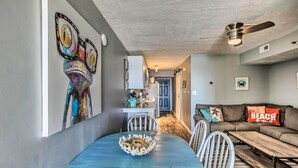 A dining area with a round table, chairs, and a decorative centerpiece. A sofa with a cushion labeled "BEACH" is visible in the background. - North Myrtle Beach Retreat w/ Ocean Views! (North Myrtle Beach)
