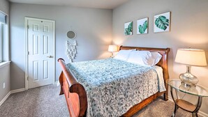 A bedroom with a bed, a bedside table with a lamp, a mirror, and wall art. - Apartment w/ Patio & Grill Access ~ 1/2 Mi to Bay! (Anacortes)