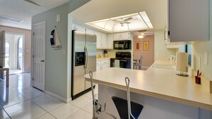 A modern kitchen with a central island, stainless steel appliances, and a ceiling fan. - Coastal Retreat w/ Grill: 4 Mi to Dtwn Cape Coral! (Cape Coral)