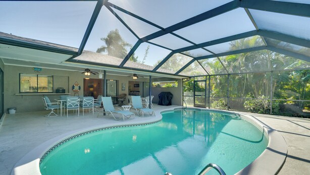 A pool area with a covered patio, lounge chairs, and a ceiling fan. - Coastal Retreat w/ Grill: 4 Mi to Dtwn Cape Coral! (Cape Coral)