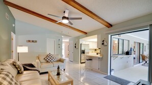 A spacious living room with a sofa, coffee table, and a ceiling fan. A kitchen is visible through an open doorway. - Coastal Retreat w/ Grill: 4 Mi to Dtwn Cape Coral! (Cape Coral)