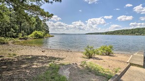 A lakeside view with a concrete dock, surrounded by trees and a clear sky.