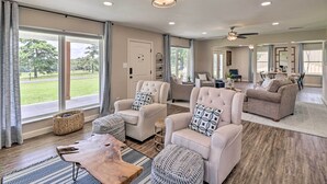 A spacious living room with large windows, a ceiling fan, and a fireplace.