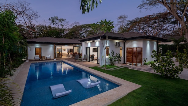 A modern house with a swimming pool, a patio with outdoor furniture, and a well-maintained garden. - Casa Prema | Modern 3BR Home in Playa Grande (Cabo Velas)