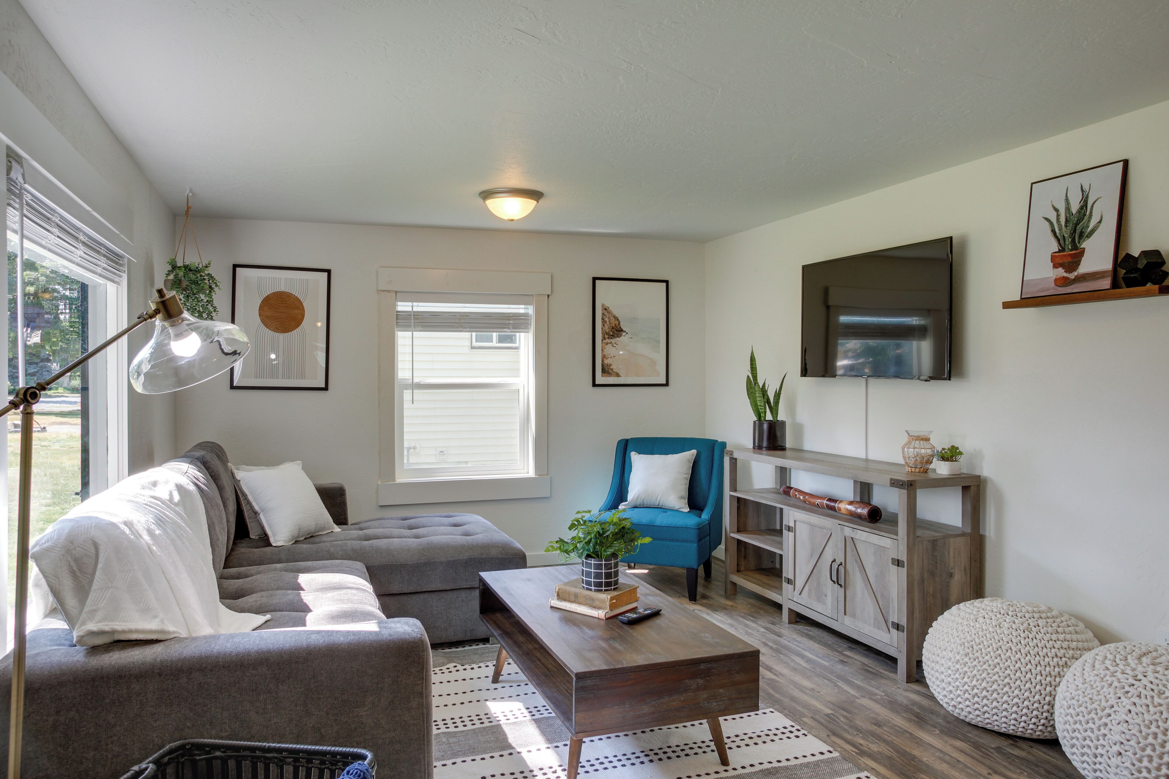 A living room with a grey sofa, a blue armchair, a wooden coffee table, and a bookshelf.