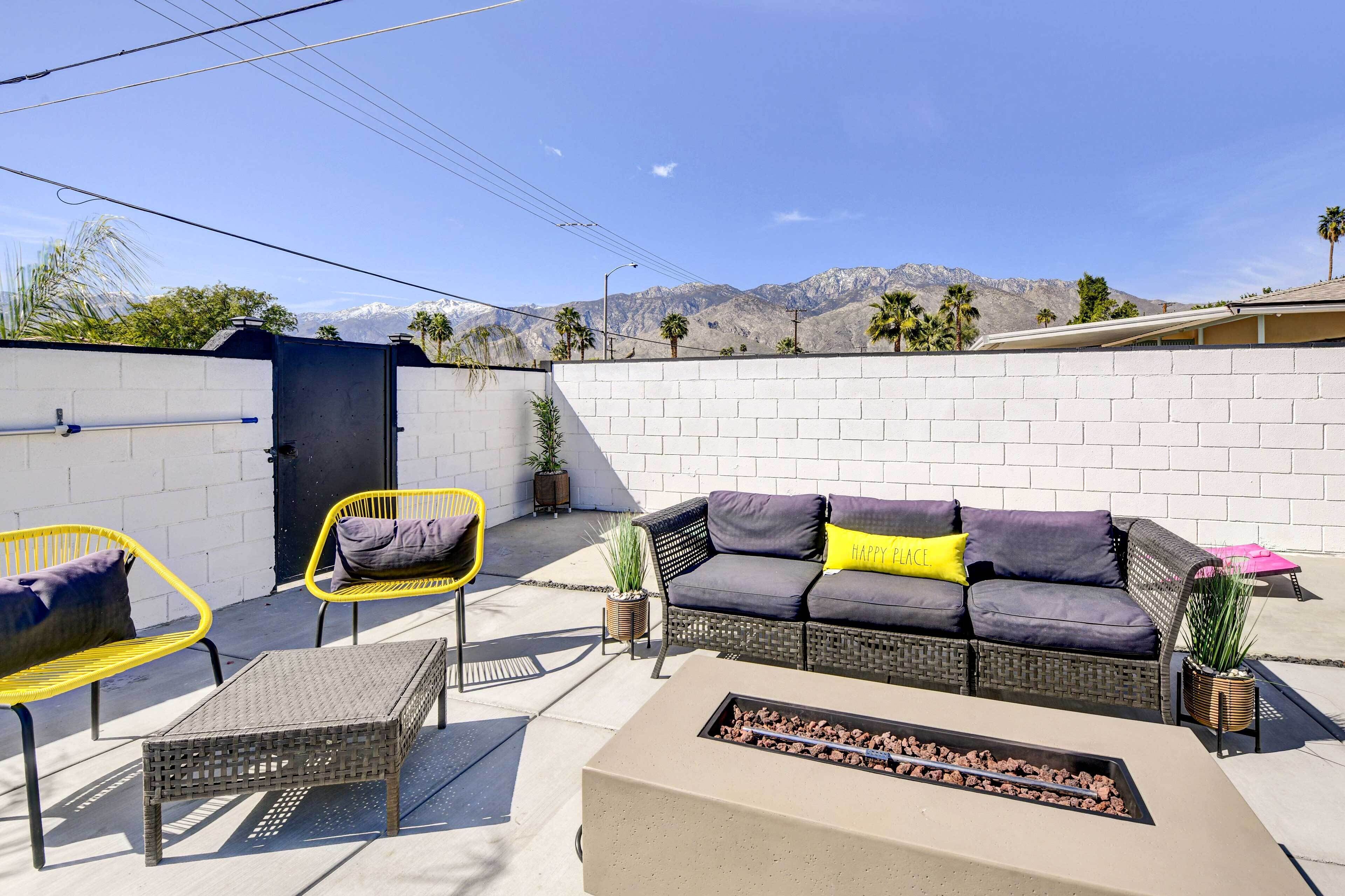 Une terrasse extérieure avec un canapé, des fauteuils et un foyer.
