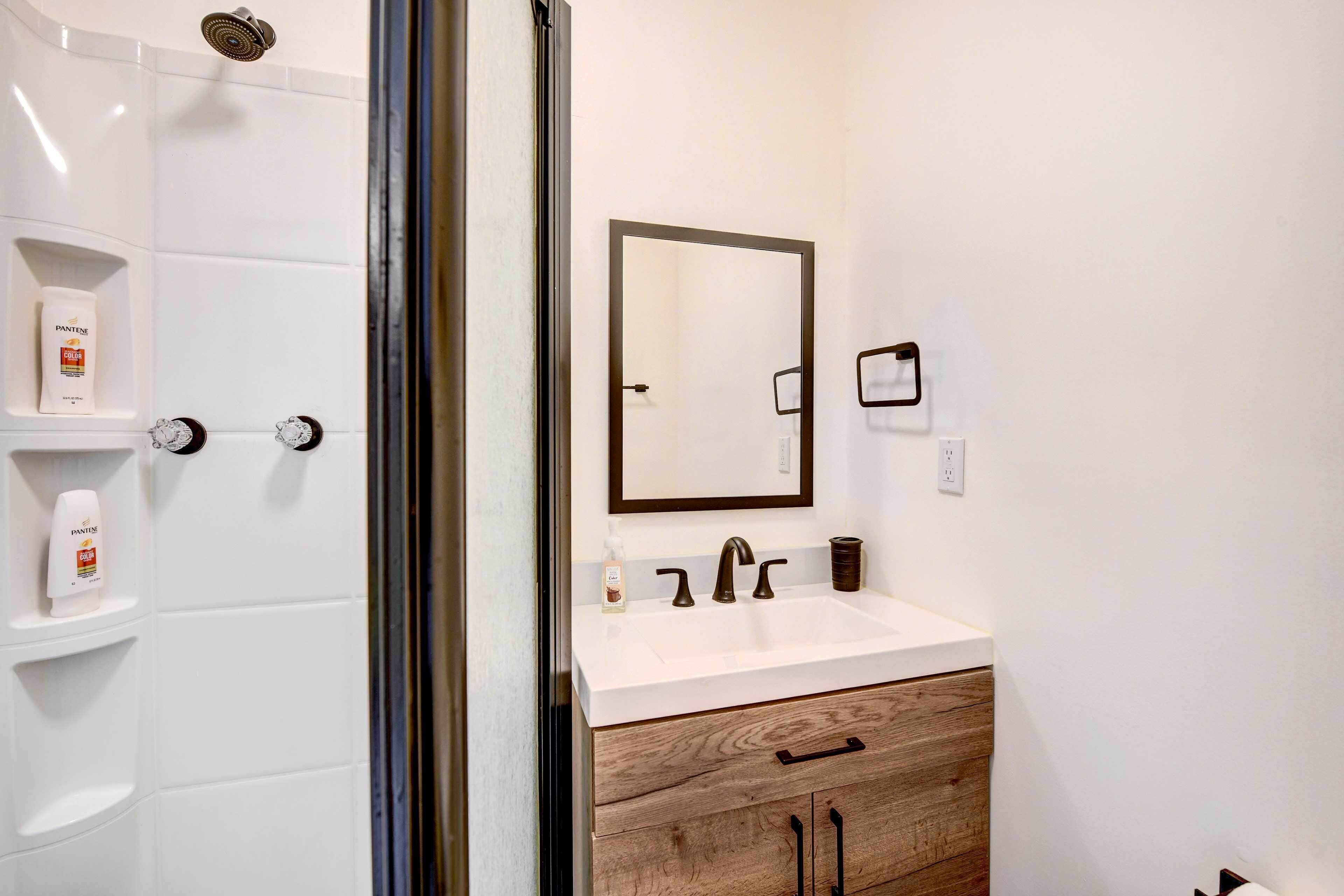 Un bagno moderno con un lavandino bianco, una cassettiera in legno e uno specchio grande.