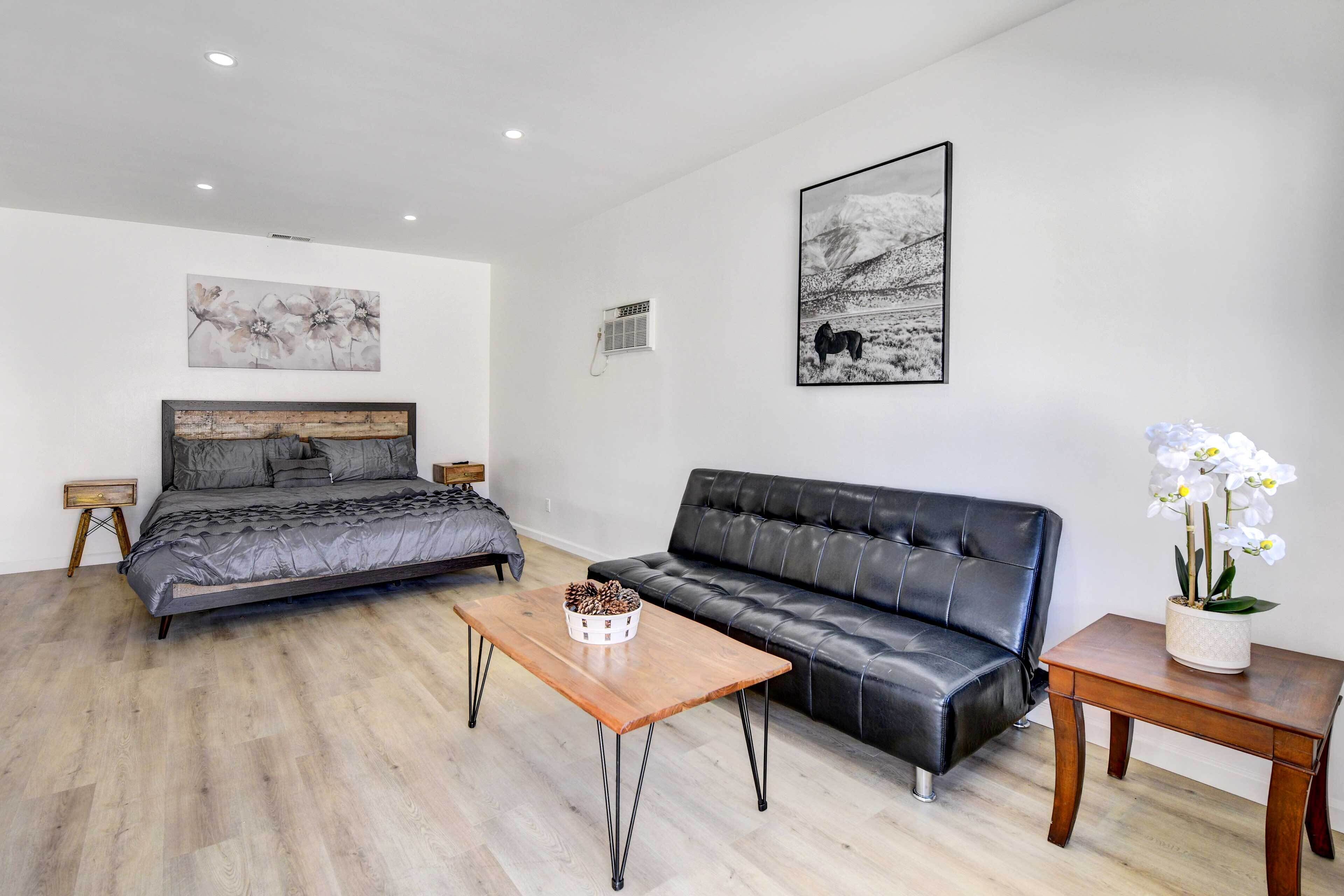 A modern bedroom with a bed, a sofa, a coffee table, and artwork on the walls.