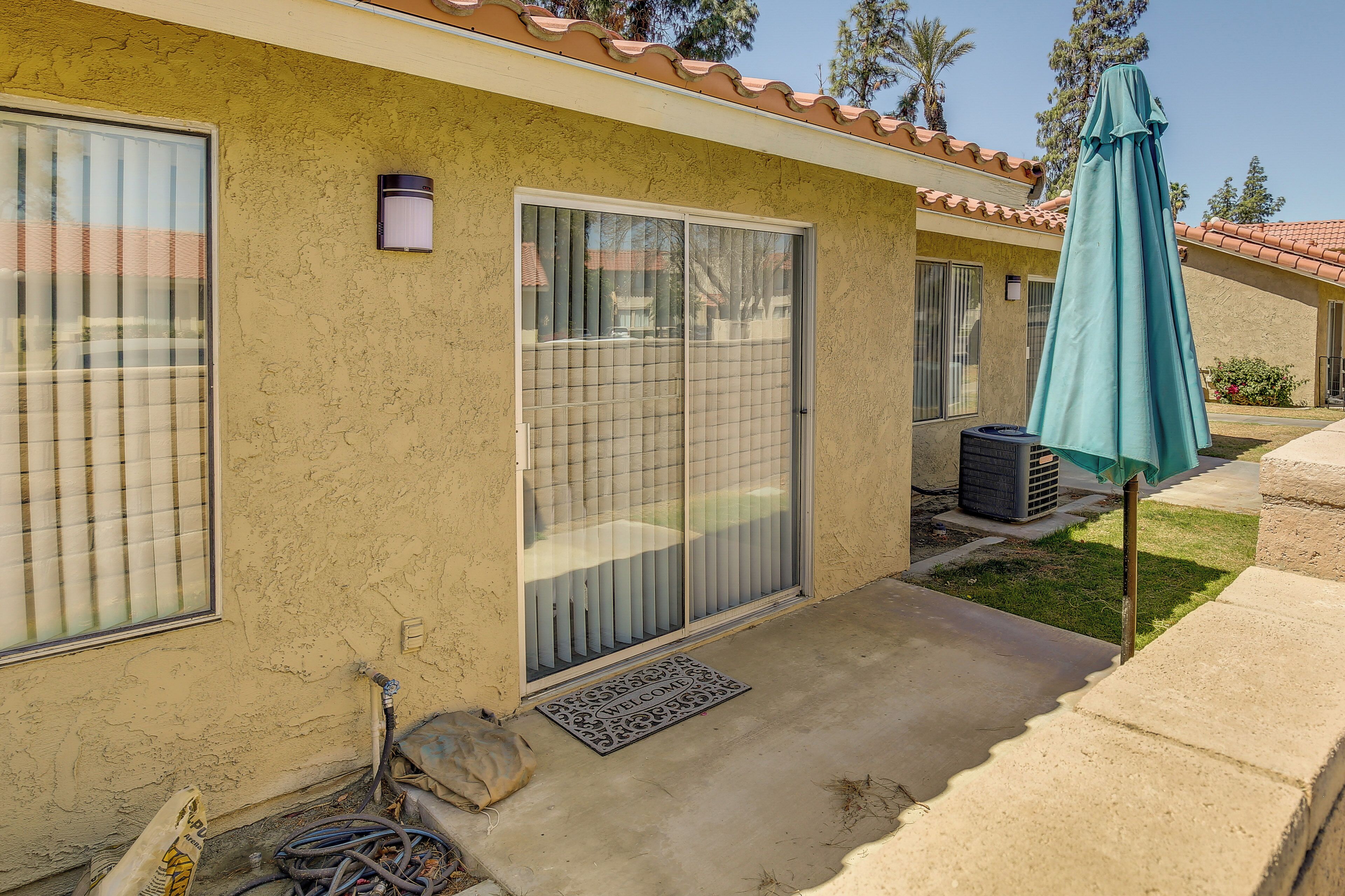 A residential building with a tiled roof, a sliding glass door, and a green umbrella.