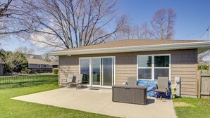 A single-story house with a covered patio, sliding glass doors, and a small outdoor seating area. - La Petit Maison - Lakefront Oshkosh Home! (Oshkosh)