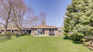 A residential house with a front yard, a patio, and a large evergreen tree. - La Petit Maison - Lakefront Oshkosh Home! (Oshkosh)