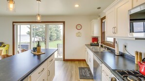 A modern kitchen with a large island, stainless steel appliances, and a view to the outdoors. - La Petit Maison - Lakefront Oshkosh Home! (Oshkosh)