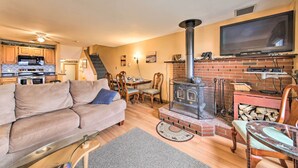 Una sala de estar acogedora con un sofá, un televisor, una chimenea y una cocina al fondo.